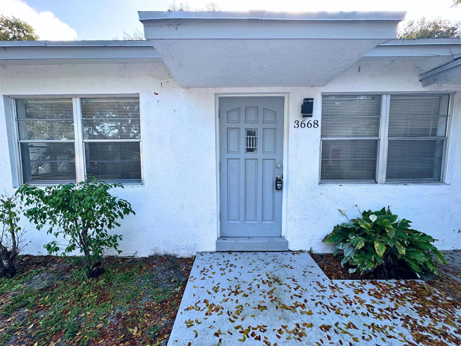 The exterior of a white house features a gray front door and two windows — 3662 Davis Road # 3668, Palm Springs FL 33461, PALM SPRINGS, FL