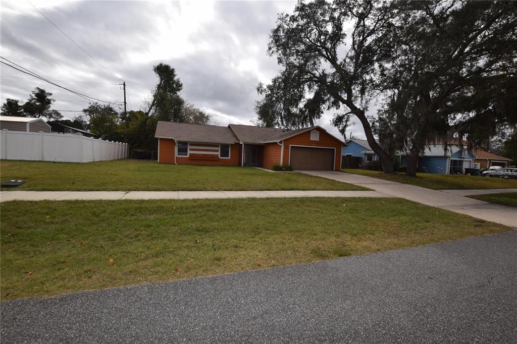 A single-story orange house with a two-car garage and a large front yard — 2585 DERBY DRIVE, DELTONA, FL