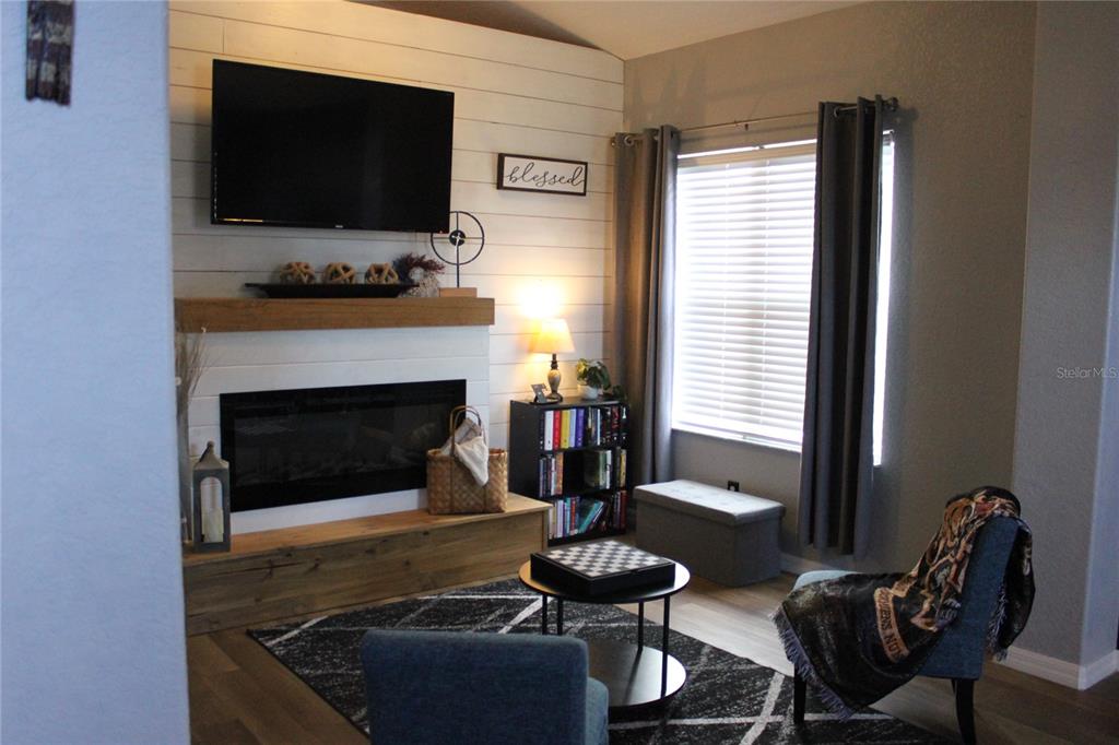 A living room features a fireplace with a wood mantel, shiplap wall, and dark furniture — 738 CORVINA DRIVE, DAVENPORT, FL