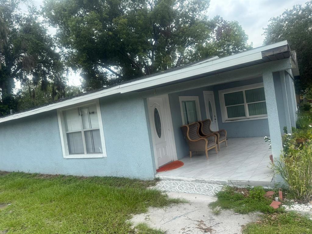 A light blue house features a covered front porch with tiled flooring and two chairs — 1509 NEIL STREET, PLANT CITY, FL