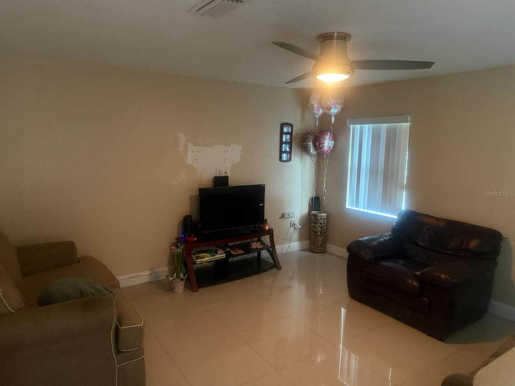 A living room features tile flooring, a ceiling fan, a television stand, and two sofas — 1509 NEIL STREET, PLANT CITY, FL