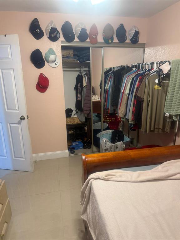 A bedroom features a mirrored sliding-door closet, a bed, and hats displayed on the wall — 1509 NEIL STREET, PLANT CITY, FL