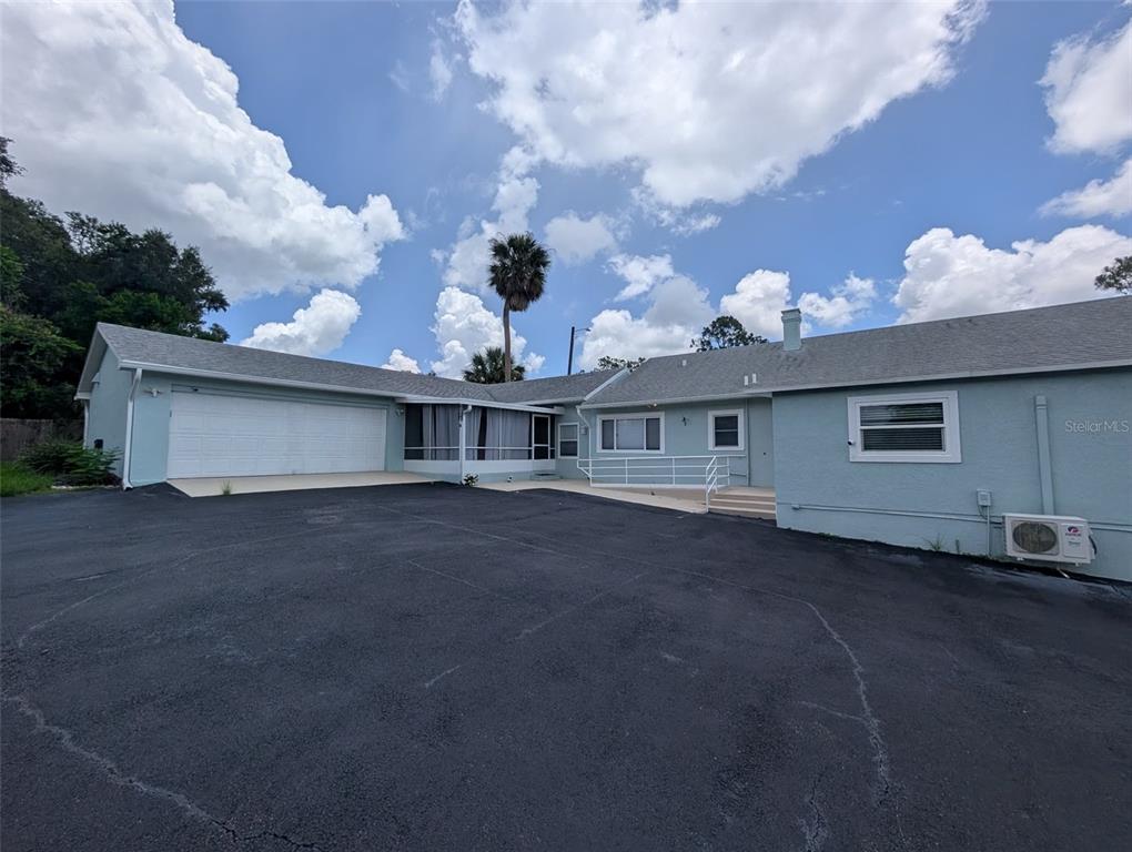 A light blue house with a large asphalt driveway, a garage, and a screened porch — 321 W PENNSYLVANIA AVENUE, DELAND, FL