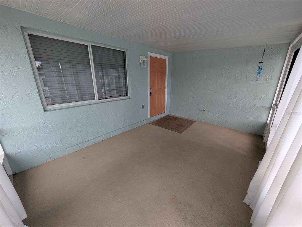 A covered porch with light blue walls, a concrete floor, and an orange entry door — 321 W PENNSYLVANIA AVENUE, DELAND, FL