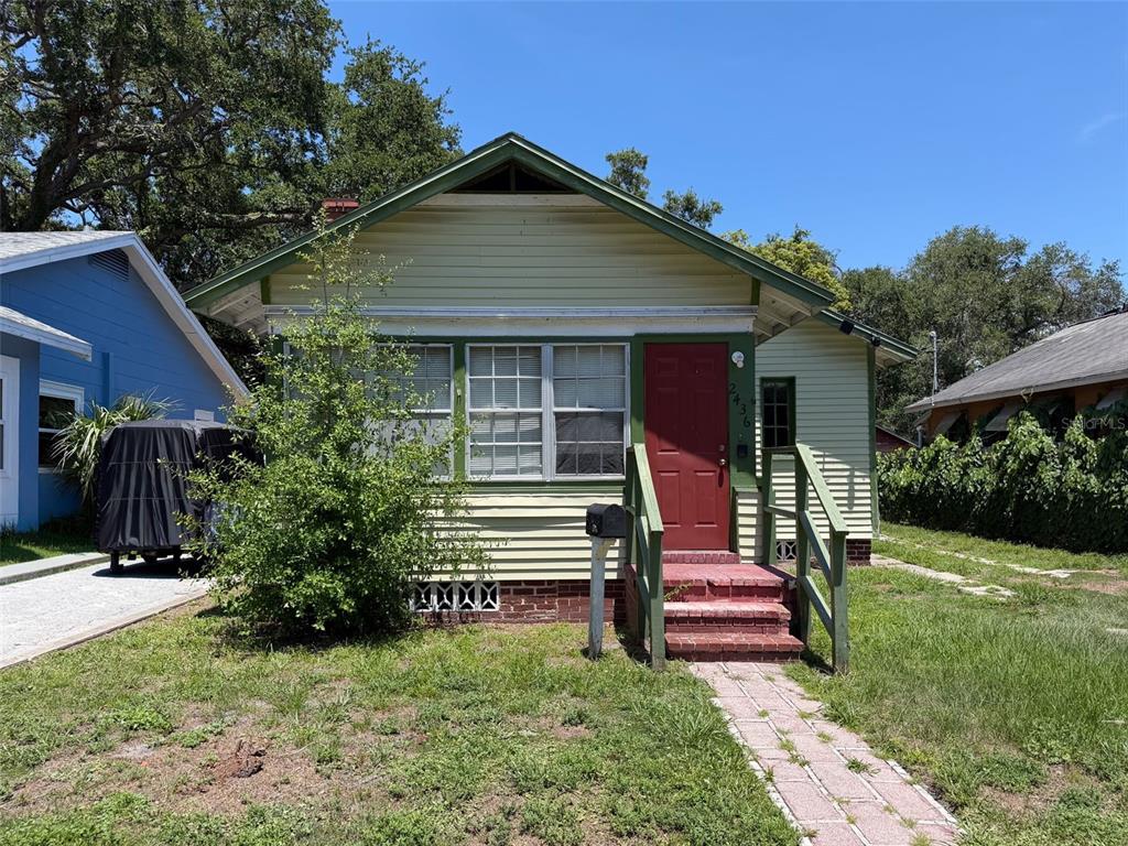 A single-story house with light green siding, a red front door, and a brick walkway — 2436 10TH STREET S, ST PETERSBURG, FL