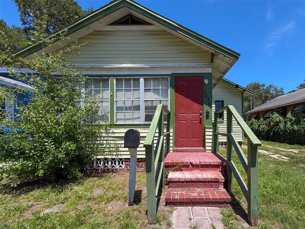 A small, light-colored house with a red front door and brick steps — 2436 10TH STREET S, ST PETERSBURG, FL