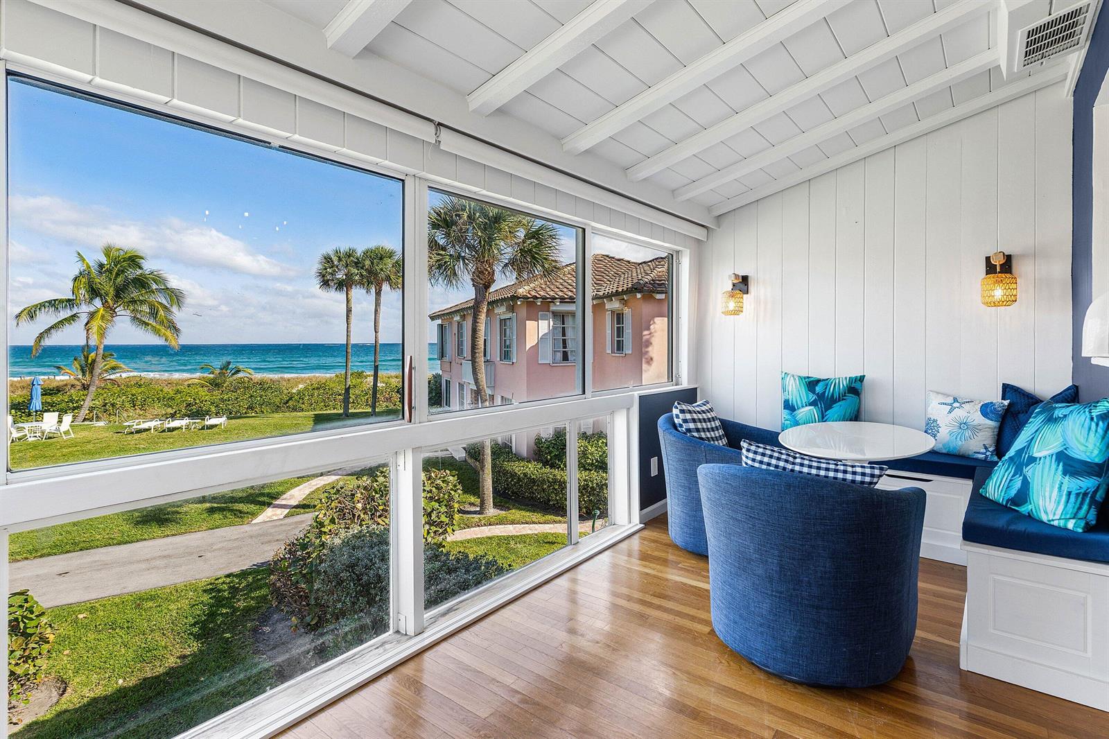 A sunroom with blue chairs and a bench overlooks a beach and palm trees — 2075 S Ocean Boulevard # 3d, Delray Beach FL 33483, DELRAY BEACH, FL
