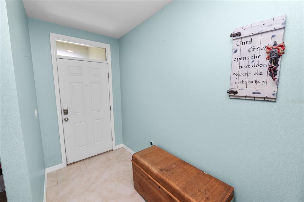 An entryway features a white front door, light blue walls, tile flooring, and a wooden chest — 3136 COUNTRY CLUB CIRCLE, WINTER HAVEN, FL