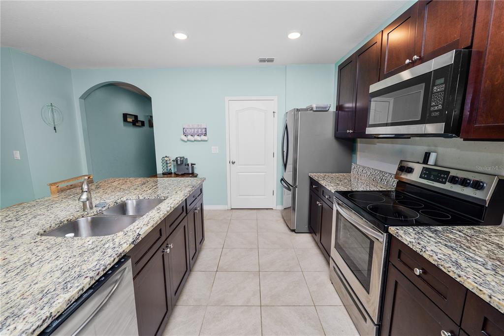 A kitchen features dark wood cabinets, granite countertops, stainless steel appliances, and light blue walls — 3136 COUNTRY CLUB CIRCLE, WINTER HAVEN, FL