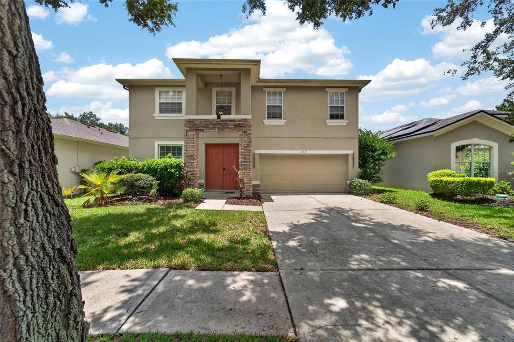 A two-story house with a tan stucco exterior, stone accents, and a two-car garage — 19128 MEADOW PINE DRIVE, TAMPA, FL