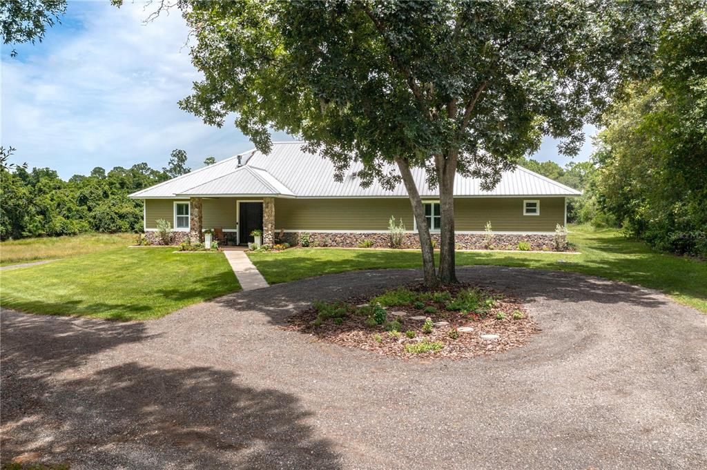 A single-story house with green siding, a stone base, and a metal roof — 3629 GREAT MASTERPIECE ROAD, LAKE WALES, FL
