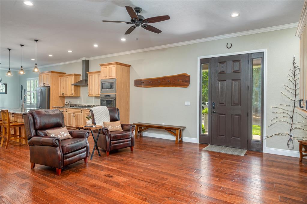 A living area with hardwood floors features two leather armchairs, a wooden bench, and kitchen cabinetry — 3629 GREAT MASTERPIECE ROAD, LAKE WALES, FL