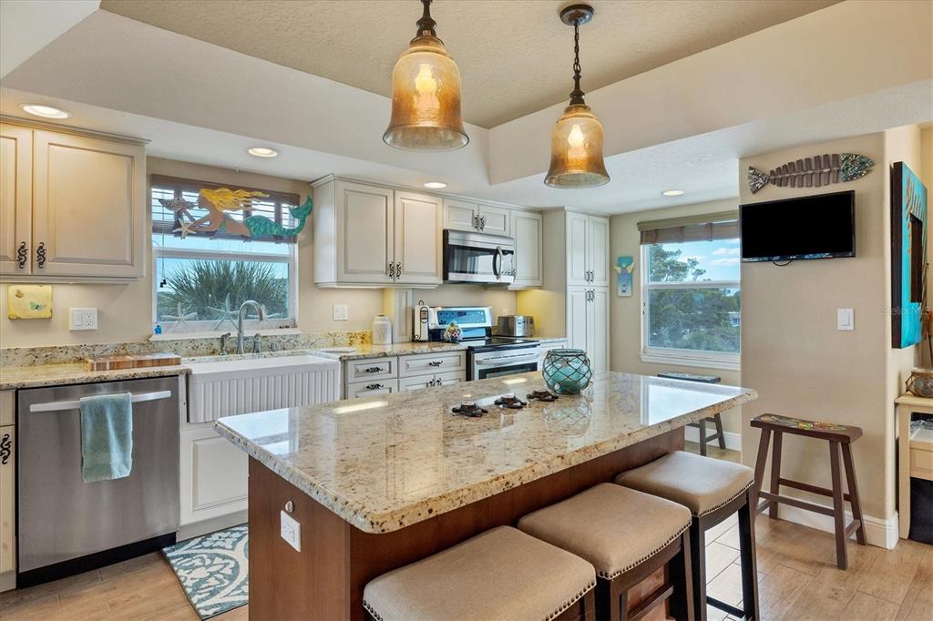 A kitchen features a granite-topped island, stainless steel appliances, and light-colored cabinetry — 4325 GULF OF MEXICO DRIVE UNIT 408, LONGBOAT KEY, FL