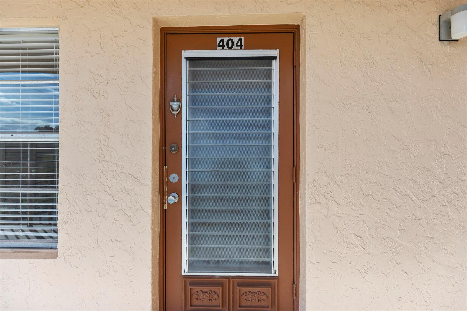 A brown front door with a louvered glass insert and the number 404 above it — 14671 Bonaire Boulevard # 404, Delray Beach FL 33446, DELRAY BEACH, FL
