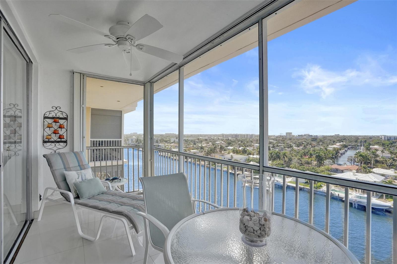 A screened-in balcony features a lounge chair, a small table, and a view of water — 303 N Riverside Drive, Pompano Beach FL 33062, POMPANO BEACH, FL