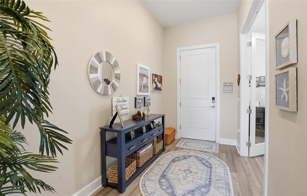 An entryway features a blue console table, a round mirror, and an oval area rug — 16408 PEBBLE RIDGE DRIVE, BRADENTON, FL