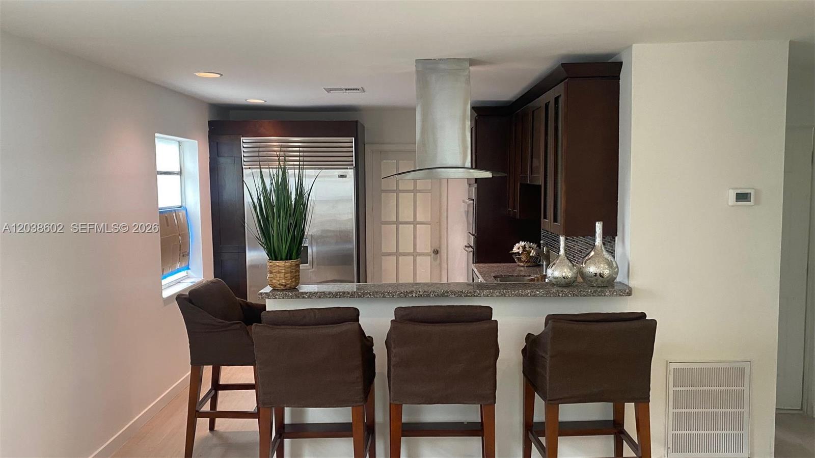 A kitchen features dark wood cabinets, a stainless steel refrigerator, and a breakfast bar — 1947 Garfield St, Hollywood FL 33020, HOLLYWOOD, FL