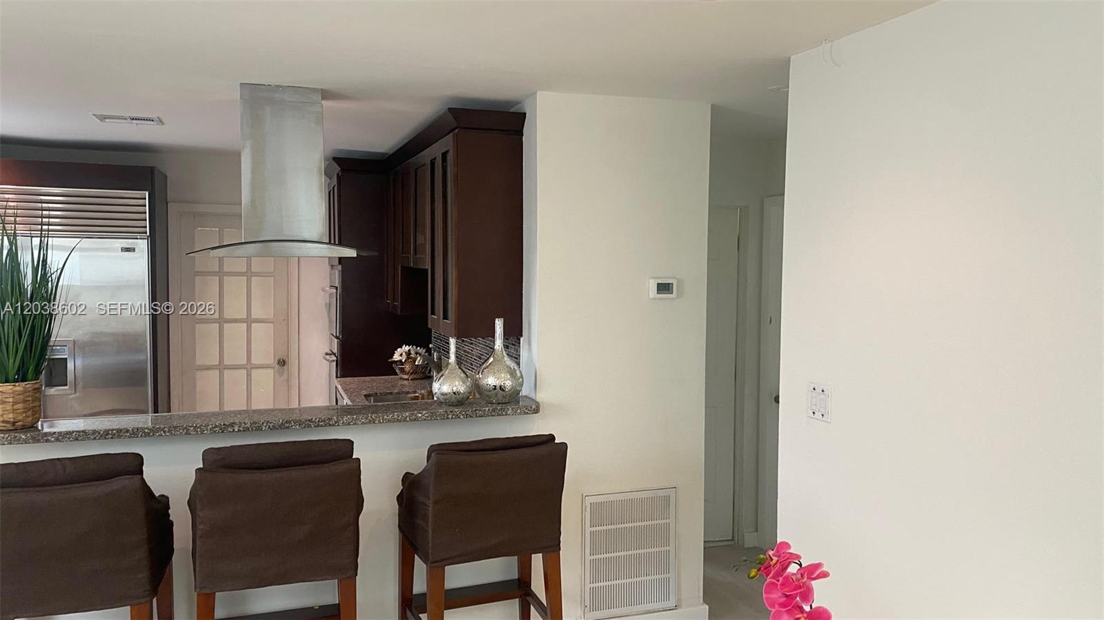 A kitchen features dark wood cabinets, a stainless steel range hood, and a breakfast bar — 1947 Garfield St, Hollywood FL 33020, HOLLYWOOD, FL