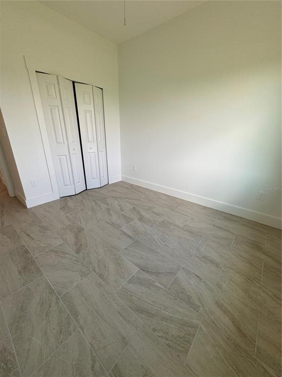 An empty room features white walls, a white bifold closet door, and light-colored tile flooring — 10490 PENDLETON AVENUE, ENGLEWOOD, FL