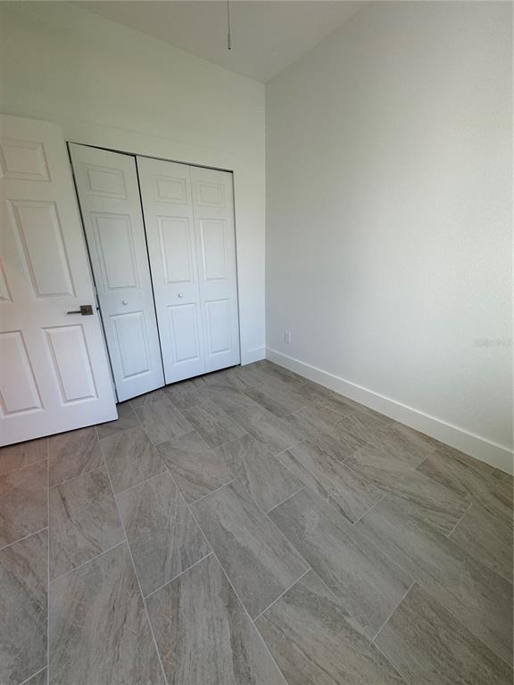 A room with white walls, light-colored wood-look tile flooring, and white closet doors — 10490 PENDLETON AVENUE, ENGLEWOOD, FL
