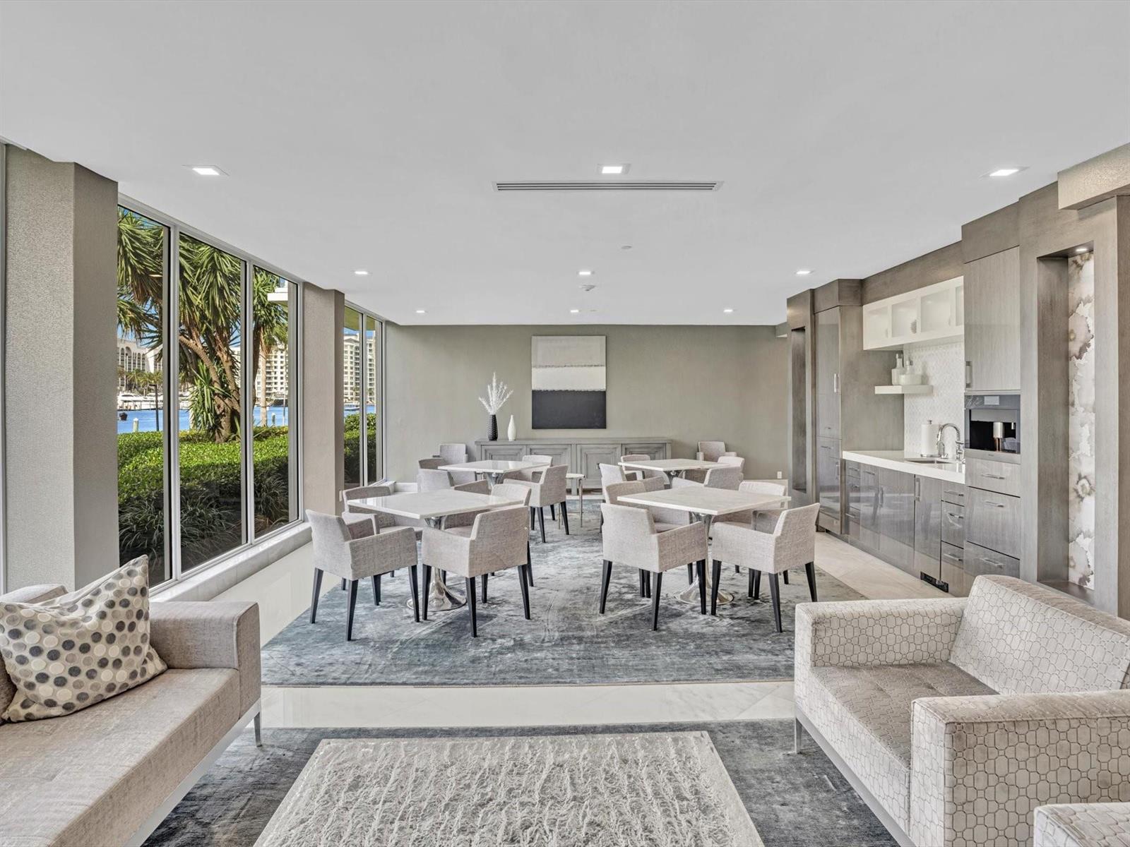 A modern lounge area features dining tables, gray upholstered chairs, a kitchenette, and floor-to-ceiling windows — 701 E Camino Real # 4e, Boca Raton FL 33432, BOCA RATON, FL