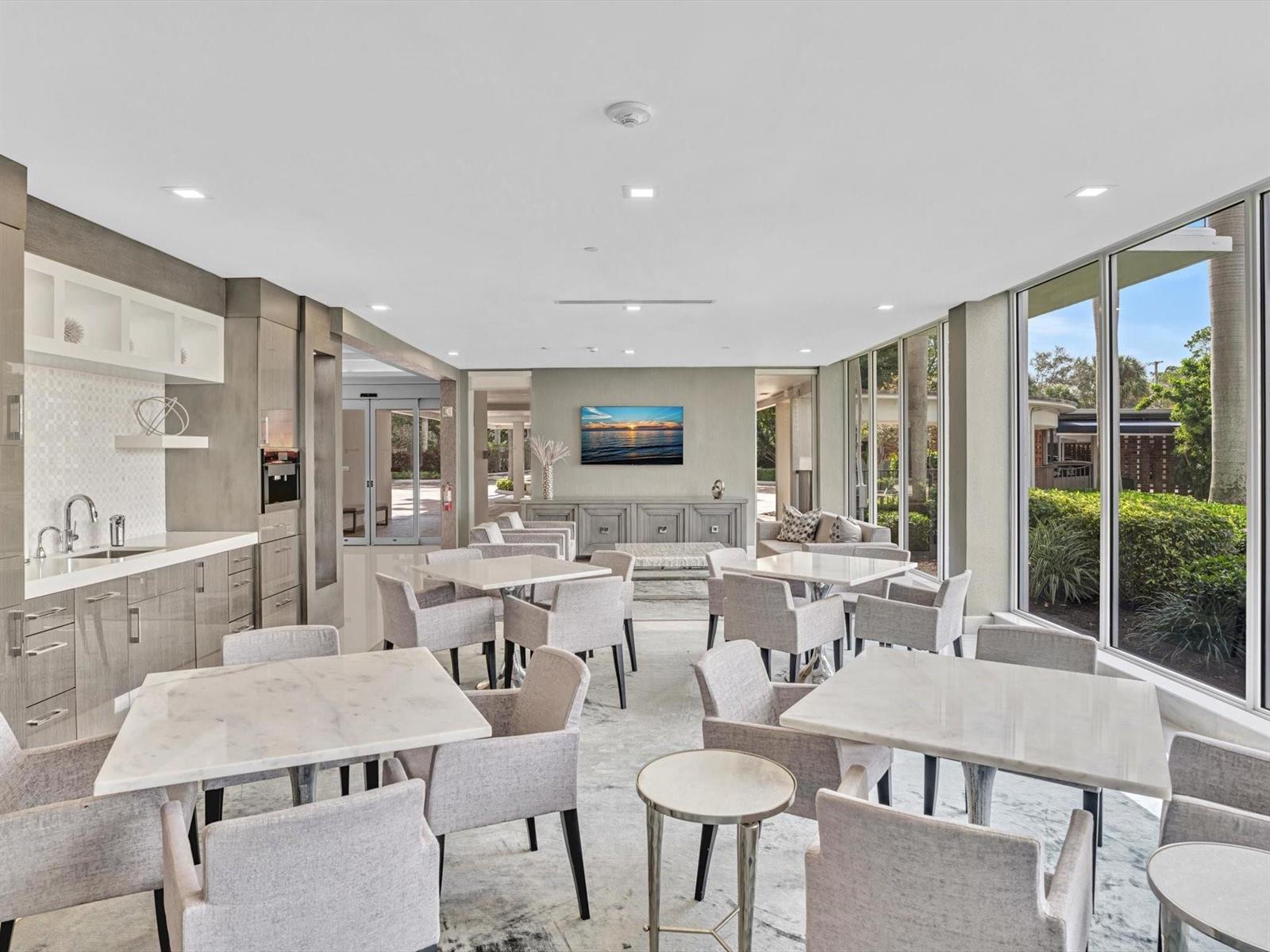 A modern lounge area features marble-topped tables, upholstered chairs, a kitchenette, and floor-to-ceiling windows — 701 E Camino Real # 4e, Boca Raton FL 33432, BOCA RATON, FL