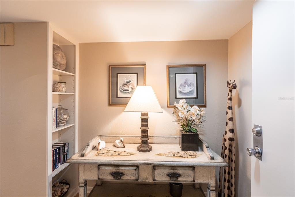 A console table with a lamp and decor sits between a bookshelf and a giraffe statue — 1055 W PEPPERTREE DRIVE UNIT 703AA, SARASOTA, FL