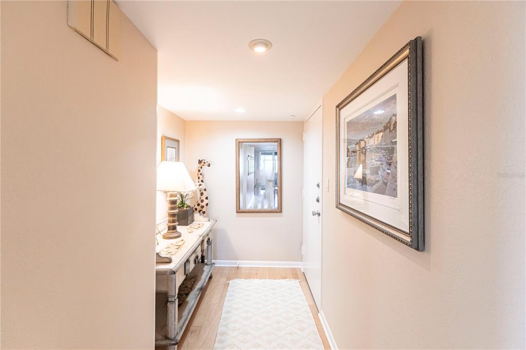 A hallway features a console table, a mirror, a framed picture, and a runner rug — 1055 W PEPPERTREE DRIVE UNIT 703AA, SARASOTA, FL