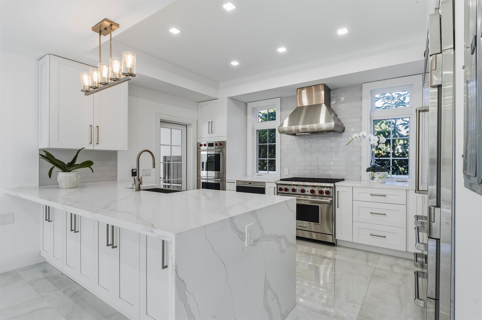 A modern white kitchen features marble countertops, stainless steel appliances, and a large center island — 259 Oleander Avenue, Palm Beach FL 33480, PALM BEACH, FL