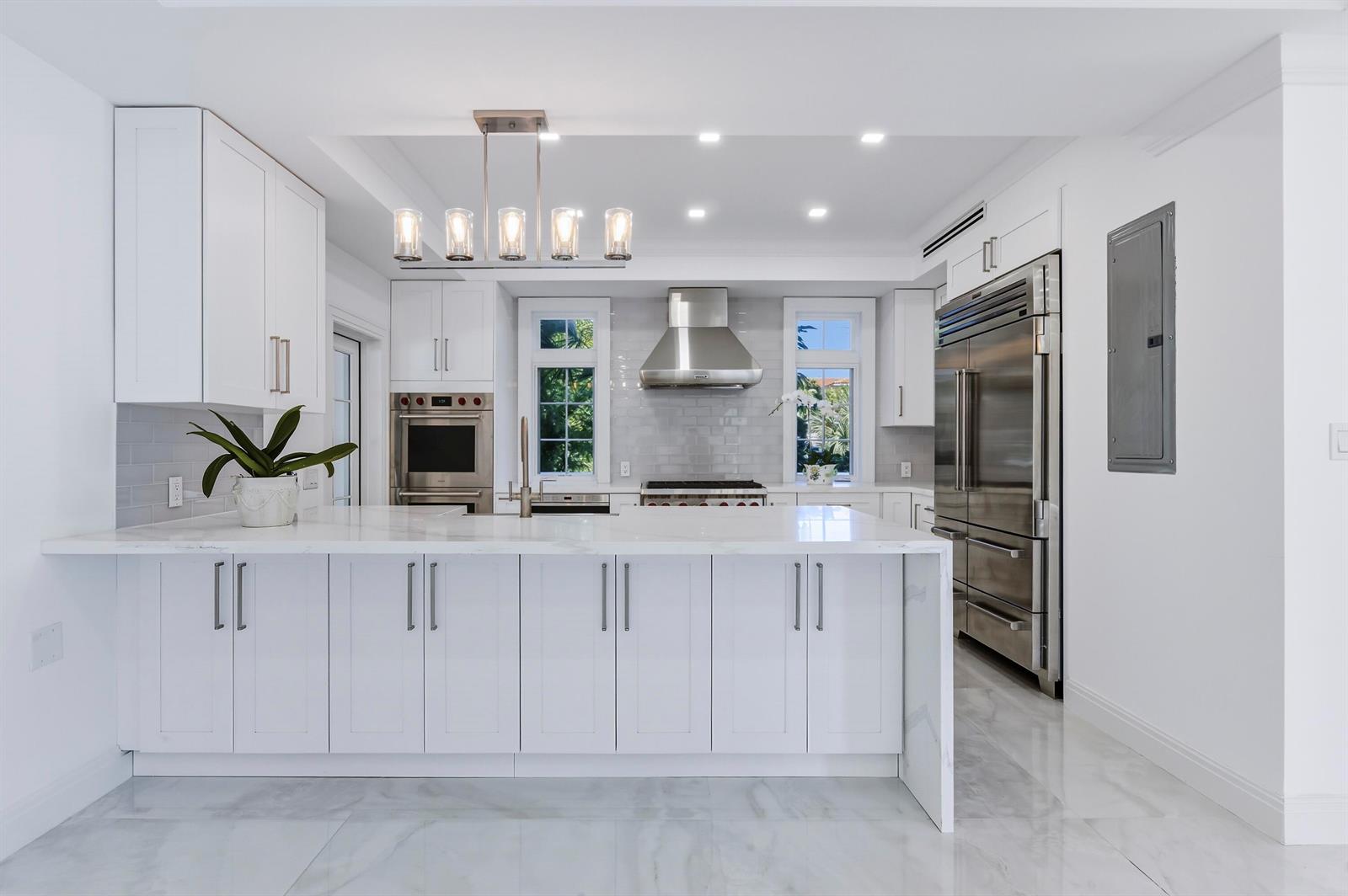 A modern white kitchen features a large marble island, stainless steel appliances, and subway tile — 259 Oleander Avenue, Palm Beach FL 33480, PALM BEACH, FL