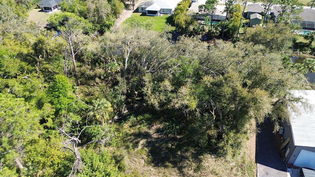 An aerial view shows a wooded, undeveloped residential lot adjacent to existing houses and a garage — NAMATKA AVENUE, NORTH PORT, FL