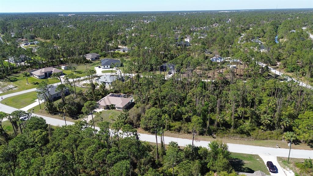 An aerial view shows several houses nestled among dense trees and paved residential streets — NAMATKA AVENUE, NORTH PORT, FL
