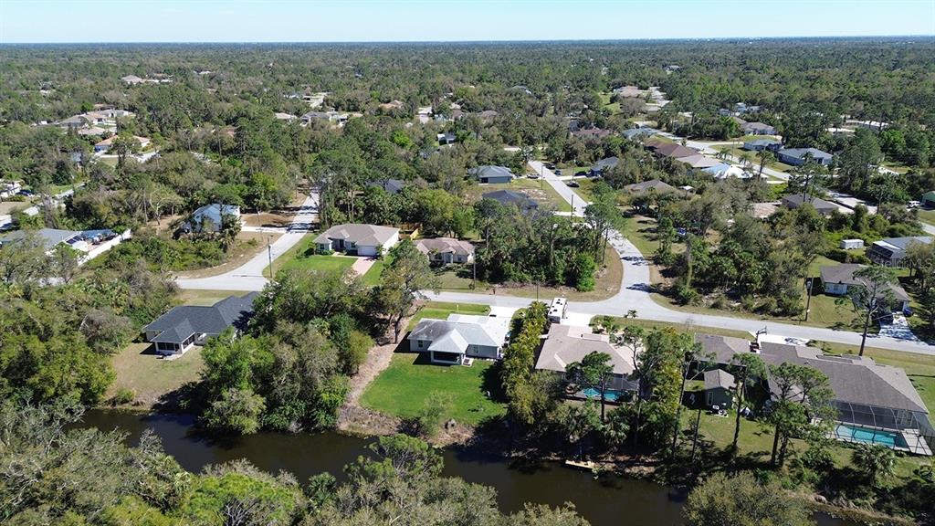 An aerial view shows several suburban houses situated along a canal surrounded by dense trees — NAMATKA AVENUE, NORTH PORT, FL