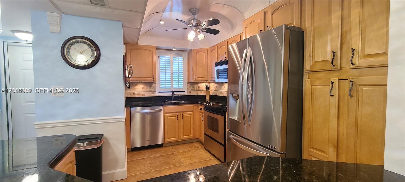 A kitchen features light wood cabinets, stainless steel appliances, and dark granite countertops — 3300 W Rolling Hills Cir # 104, Davie FL 33328, DAVIE, FL
