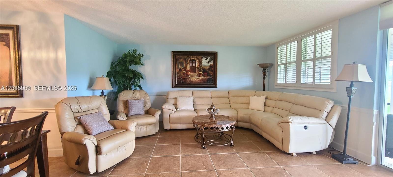 A living room features a beige sectional sofa, a matching armchair, and tile flooring — 3300 W Rolling Hills Cir # 104, Davie FL 33328, DAVIE, FL