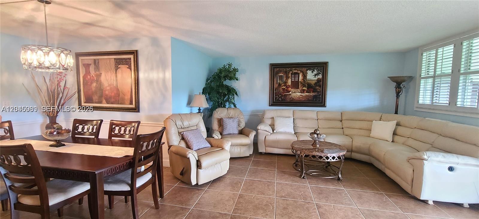 A living and dining area features tile flooring, a beige sectional, and a wooden table — 3300 W Rolling Hills Cir # 104, Davie FL 33328, DAVIE, FL