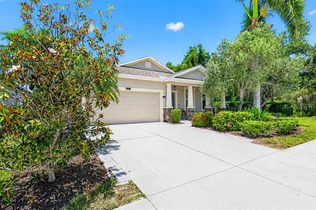 A single-story house with a beige exterior, a two-car garage, and a concrete driveway — 5512 MANG PLACE, SARASOTA, FL