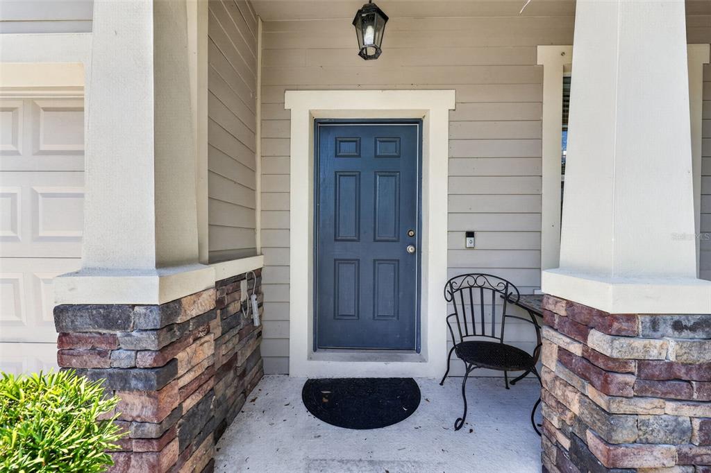 A front porch features a blue door, stone-clad columns, and a small metal chair — 5512 MANG PLACE, SARASOTA, FL