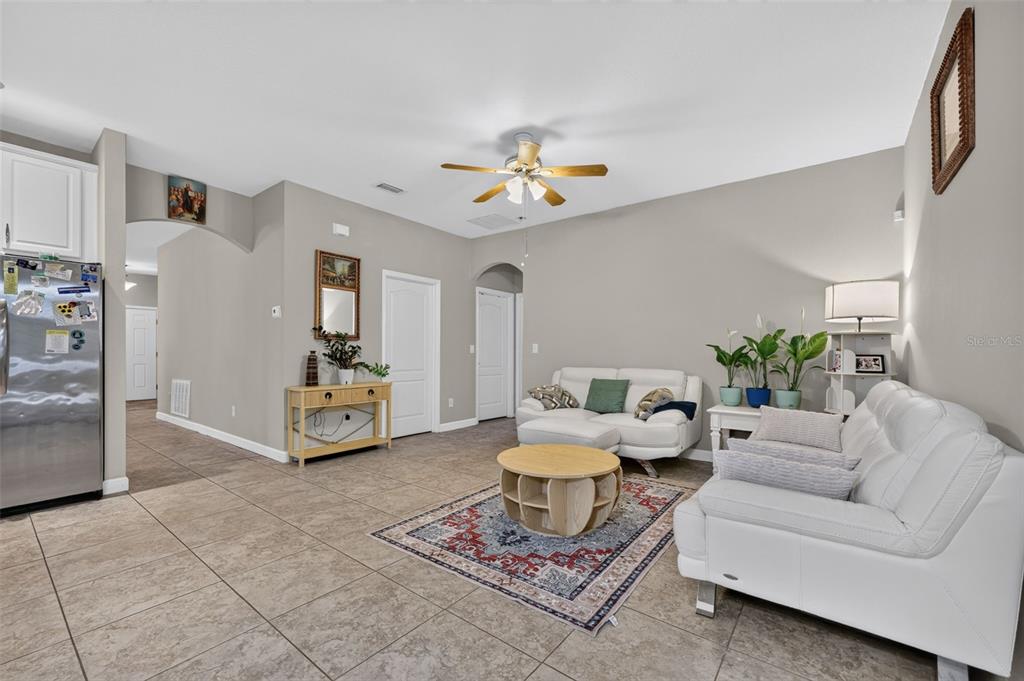 A living room features tile flooring, white leather sofas, a round coffee table, and a rug — 5512 MANG PLACE, SARASOTA, FL