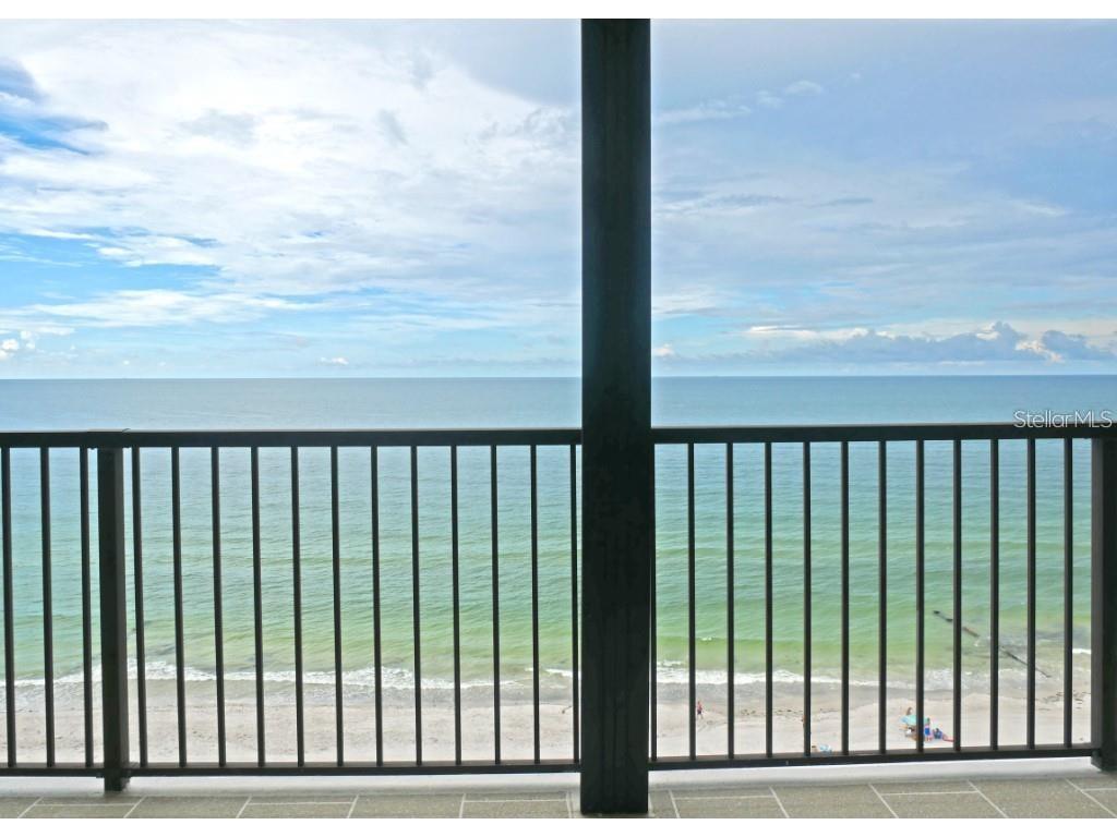A balcony with a dark metal railing overlooks a sandy beach and the ocean — 15000 GULF BOULEVARD UNIT 1108, MADEIRA BEACH, FL