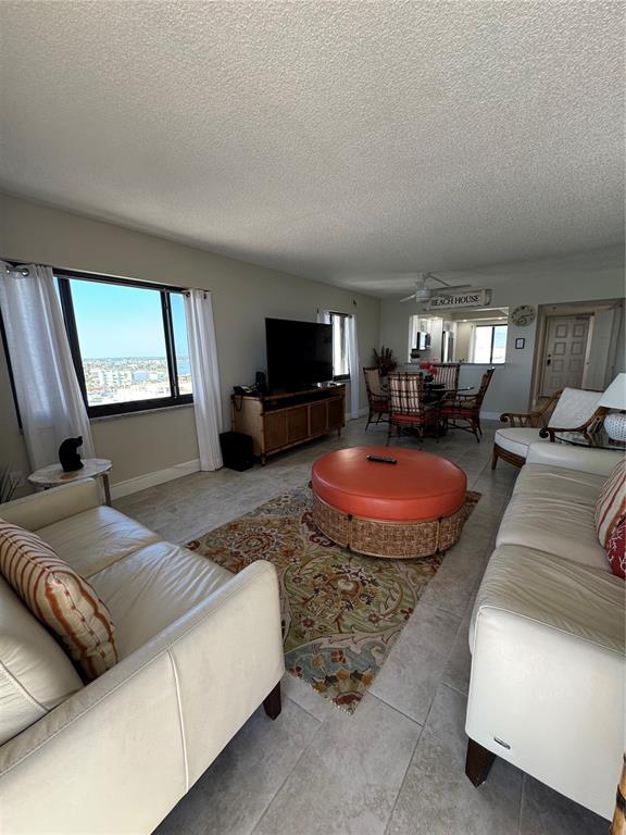 A living room features two white sofas, a round orange ottoman, and a dining area — 15000 GULF BOULEVARD UNIT 1108, MADEIRA BEACH, FL