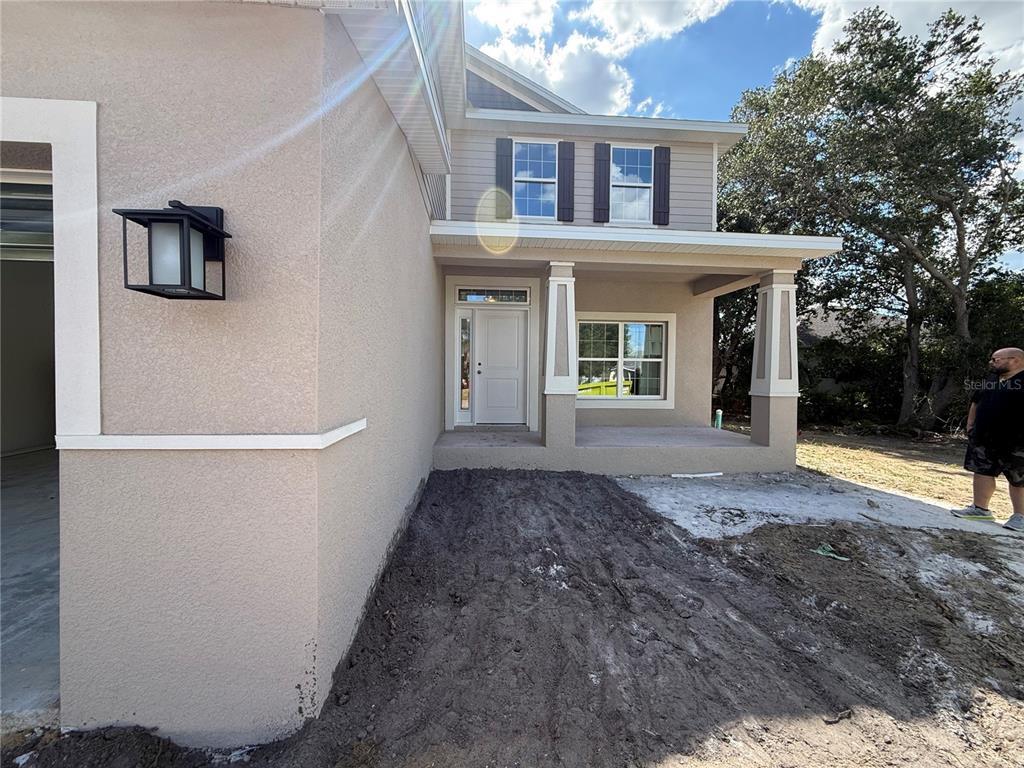 The exterior of a two-story house features a covered front porch and unfinished landscaping — 453 SAN AMBROSIO STREET, PUNTA GORDA, FL