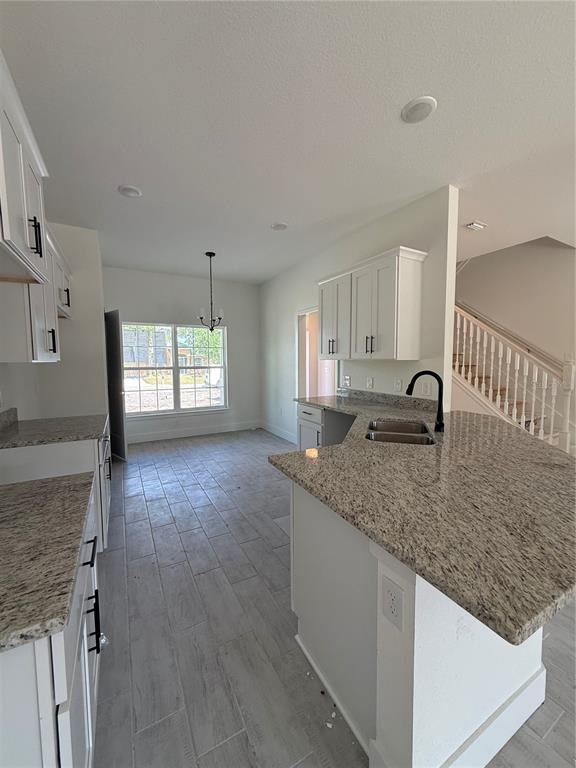 A kitchen with white cabinets, granite countertops, and tile flooring overlooks a dining area — 453 SAN AMBROSIO STREET, PUNTA GORDA, FL