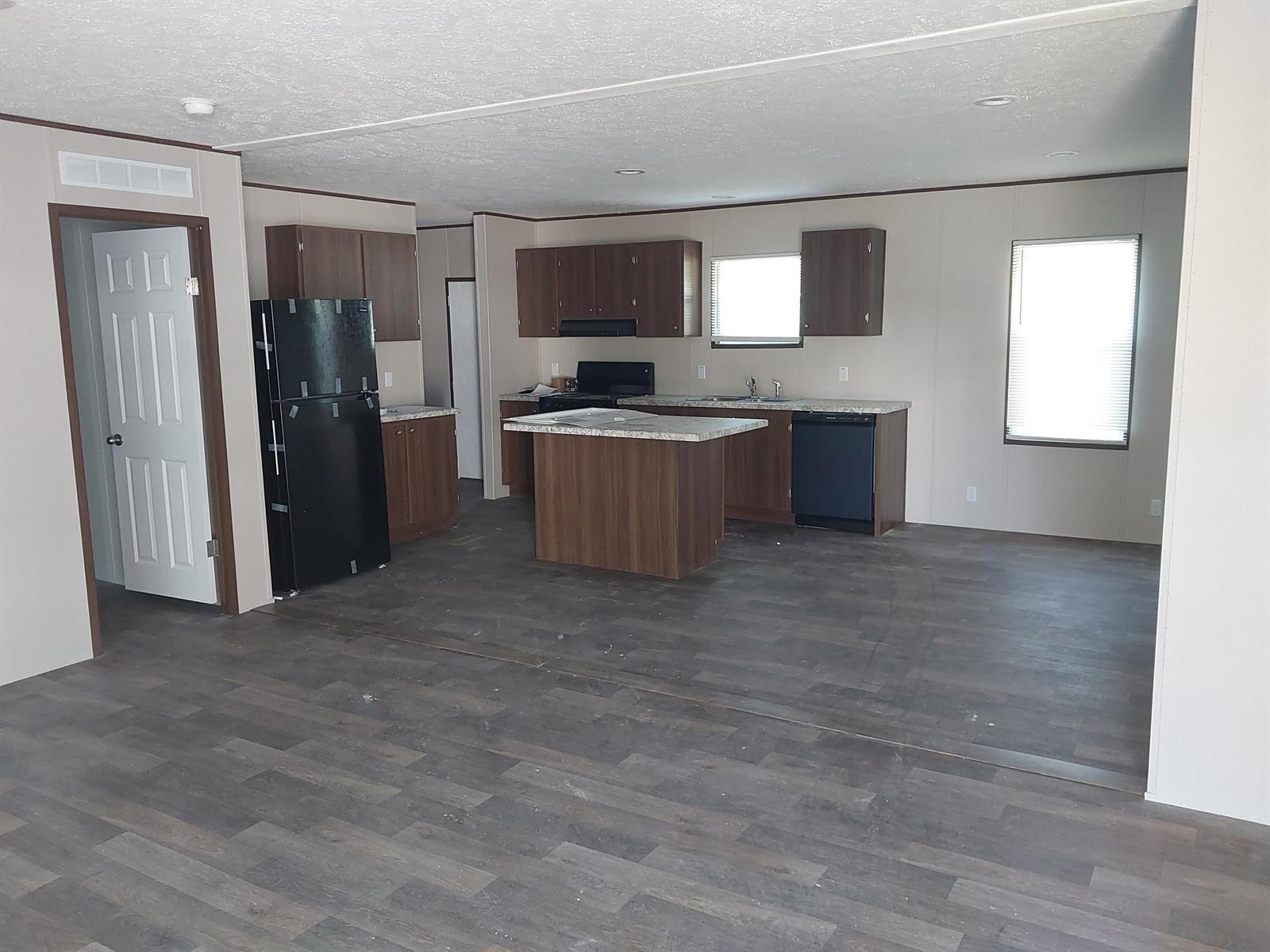 An open-concept kitchen features dark wood cabinets, a center island, and black appliances — 506 SE San Jose Street, Stuart FL 34994, STUART, FL