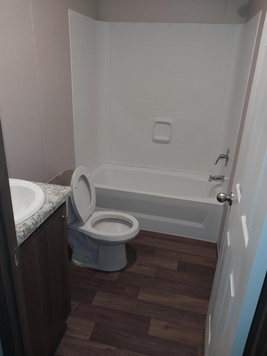 A bathroom featuring a vanity, a toilet, and a white bathtub with a shower surround — 506 SE San Jose Street, Stuart FL 34994, STUART, FL