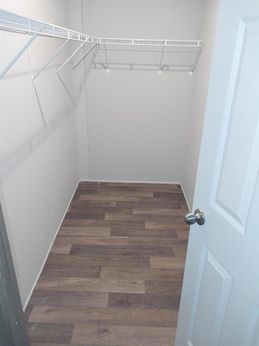 A walk-in closet features light-colored walls, wood-look flooring, and white wire shelving — 506 SE San Jose Street, Stuart FL 34994, STUART, FL