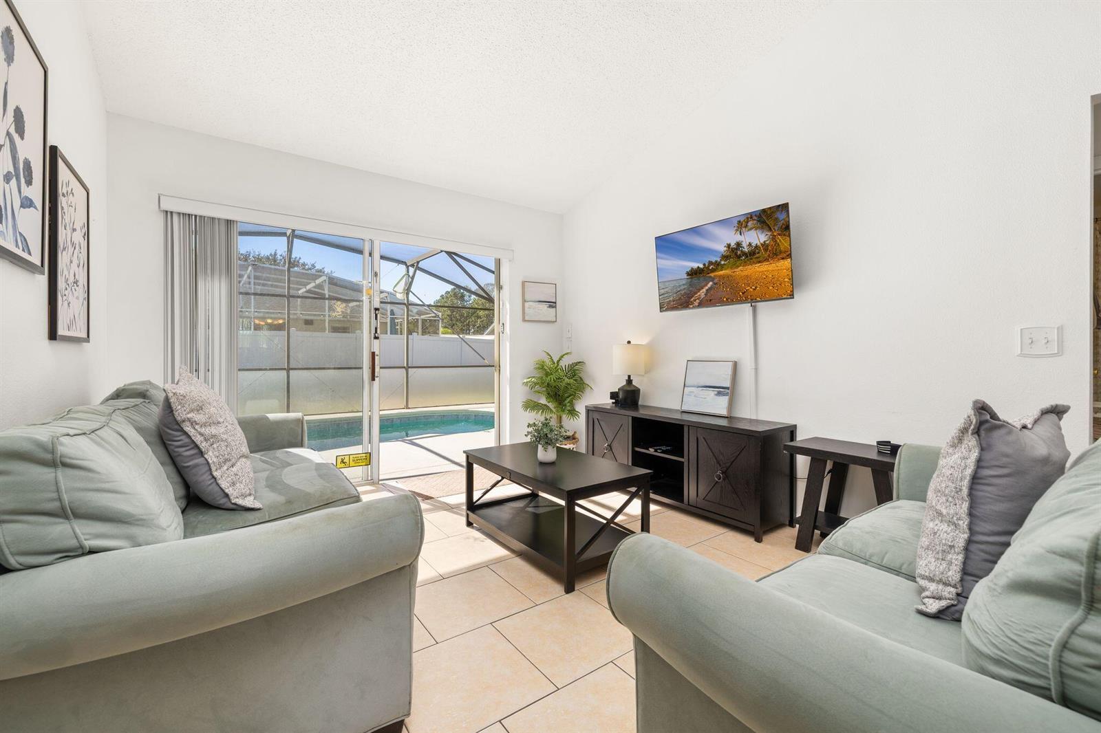 A living room features two light green sofas, a coffee table, and a sliding glass door — 128 Pine Cone Drive, Davenport FL 33897, DAVENPORT, FL