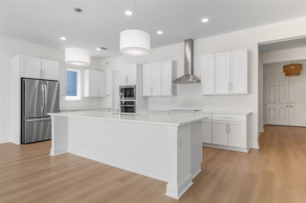 A modern kitchen features white cabinetry, a large central island, and stainless steel appliances — 24 CINNAMON BEACH WAY, PALM COAST, FL