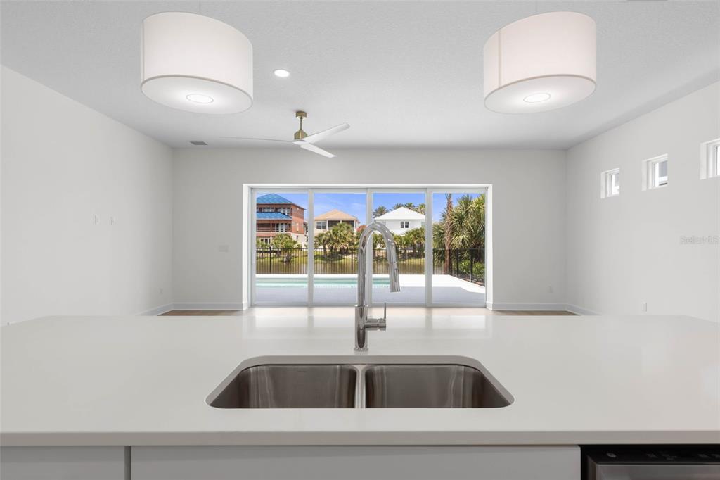 A kitchen island with a double sink overlooks a living area with sliding glass doors — 24 CINNAMON BEACH WAY, PALM COAST, FL