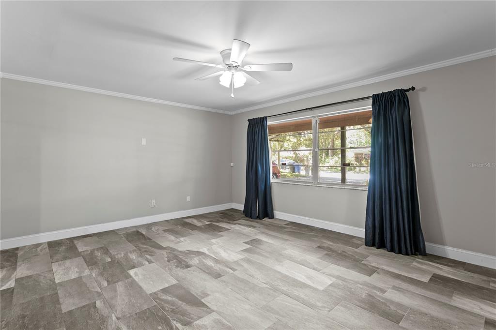 An empty room features gray tile flooring, light gray walls, and a ceiling fan — 6928 GREENHILL PLACE, TAMPA, FL